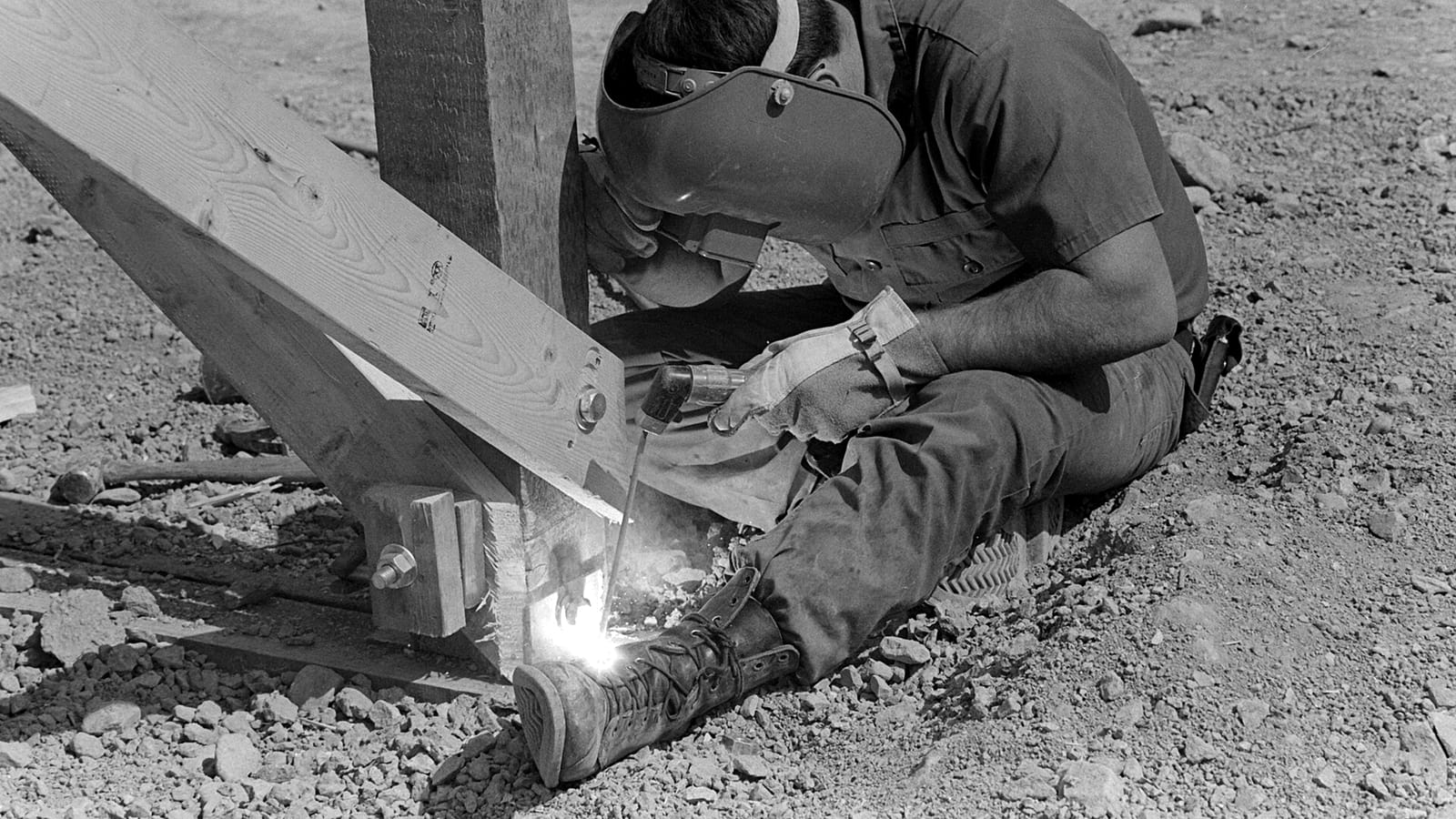 A welder in a mask joining a steel brace on a construction site